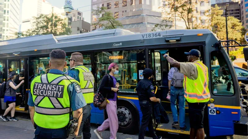 Professional transit security officer standing guard at a busy transit terminal, ensuring passenger safety.